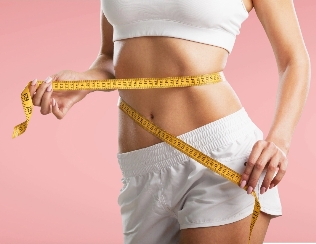 Close-up of a woman measuring her waist with a yellow tape measure, dressed in white sports attire against a soft pink background, emphasizing health, fitness, and self-improvement